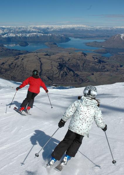 Skiers enjoying Treble Cone's groomed trails and stunning view over Lake Wanaka